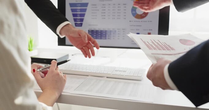 Business executives and team in finance discussion. Hands gesture over accounting charts and report data near a computer dashboard. Hands point at graphs. Concise concept of finance teamwork.