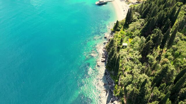 Birds eye view, hight shot low flying over the Corfu, Greece coast line and cyprus pines. Stunning clear waters. Shot on a 4k at 60 fps on a DJI Mini 3 Pro in Raw Footage (uncolorgraded), D-Log film