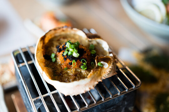Kani Miso, crab miso served in shell bowl on top with elevated premium toppings with salmon roe, caviar and sliced ​​scallions. Rich crab tomalley delicacy, creamy seafood specialty from Japan.