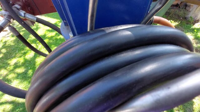 Worker holding a thick black high pressure hydraulic hose coiled on a hook
