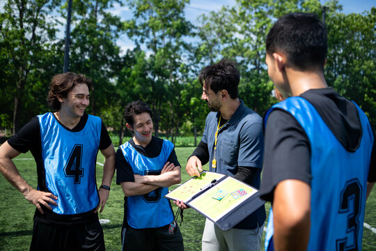 Soccer coach explaining tactics and game strategy to players during a team briefing