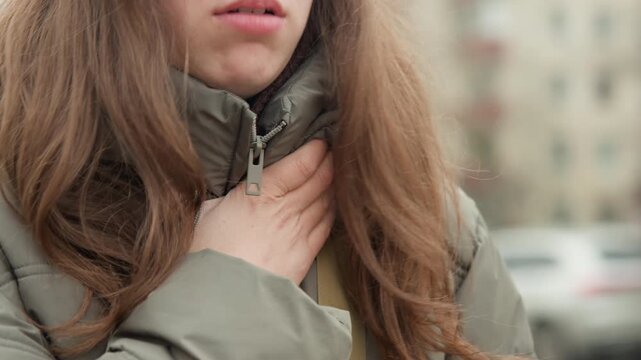 Closeup woman hand on chest beneath zipped jacket collar, subtle inhale and exhale visible in lips and throat detailed frames capture gesture of anxiety, relief and sincerity, textured hair and winter