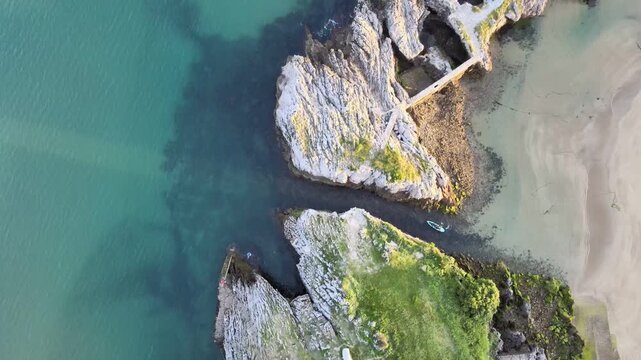 Aerial drone footage of a canoe passing through a channel carved out between the cliffs at Islares, Castro Urdiales, Cantabria