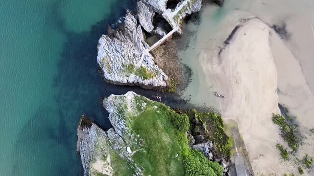 Aerial video of a canoe passing through a channel carved out between the rocks in the sea, at Islares, Castro Urdiales, Cantabria