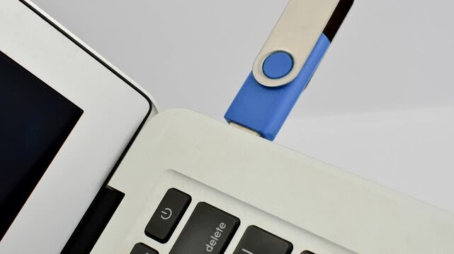 Detail of a USB drive next to a laptop, representing portable technology and fast data transfer.