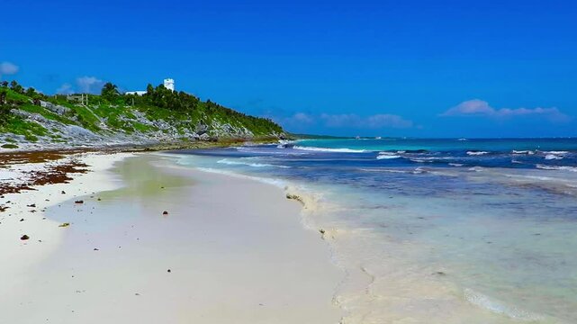 Tropical white sandy beach with waves and green vegetation. Sunny day on the whit beach. Romantic ocean coastline. Travel footage, windy day by the ocean. White beach and wave