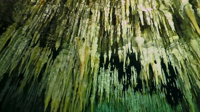 Underwater cenote with stalactites. Cave limestone formation under the water surface with the light reflection. Cenote tunnel exploration. Travel footage, cave diving.