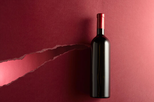 Bottle of red wine on a dark red background.