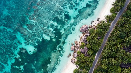 Fototapeta premium Stunning aerial view of a pristine tropical shoreline with turquoise water, granite boulders, lush palm trees, and a coastal road in the Seychelles.