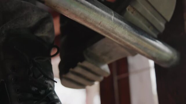 Closeup of rugged boot on metal surface. Detailed shot of footwear crushing metallic bar outdoors. Dynamic image capturing sturdy boot pressed against weathered metal strip in urban environment