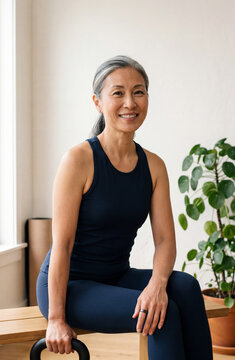  Portrait of a fit mature East Asian woman resting with kettlebell in home gym wearing health tracking ring