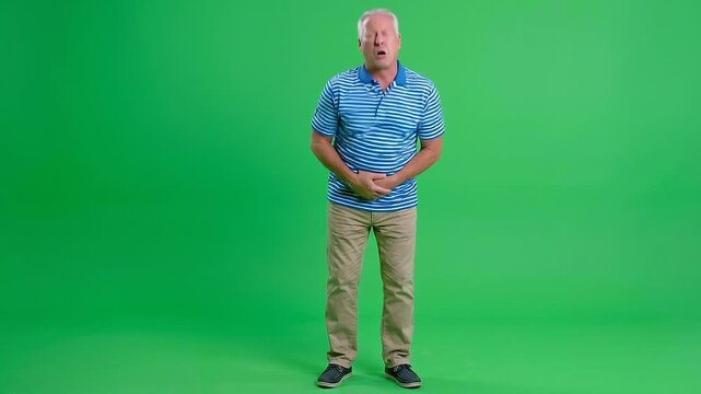 Older Caucasian man experiencing severe stomach pain and nausea, sticking tongue out in disgust while holding his abdomen.