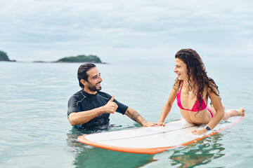 Obraz premium Portrait of a young couple surfing at the beach, holding surfboards, having fun together ocean waves, healthy life holidays adventure concept