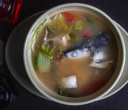 over head photo of fish tamarind soup or fish sinigang with vegetables on a white bowl.