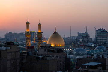 Fototapeta premium Karbala, Iraq - December 28, 2025: Golden dome and illuminated minarets of the Imam Hussain Shrine glowing at dusk in Karbala, Iraq