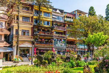 Fototapeta premium A view across a park towards flower decorated buildings in the centre of Sapa, Vietnam, in the morning