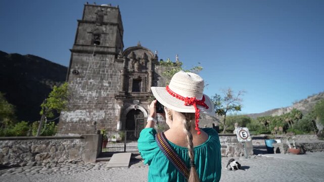Senior woman enjoys taking photos in front of San Javier Mission close to Loreto at sunrise, showing her excitement and joy