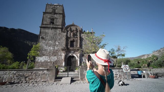 A senior woman smiles and takes photos in front of San Javier Mission during sunrise near Loreto in Baja California Sur Mexico