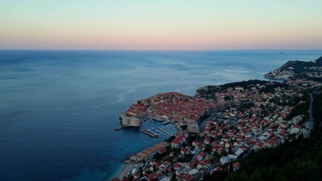 Dubrovnik old town, Croatia. Long distance panning shot shwoing the castle walls, red roofs, ocean, harbour. Shot on a 4k at 60 fps on a DJI Mini 3 Pro in Raw Footage (uncolorgraded), D-Log film