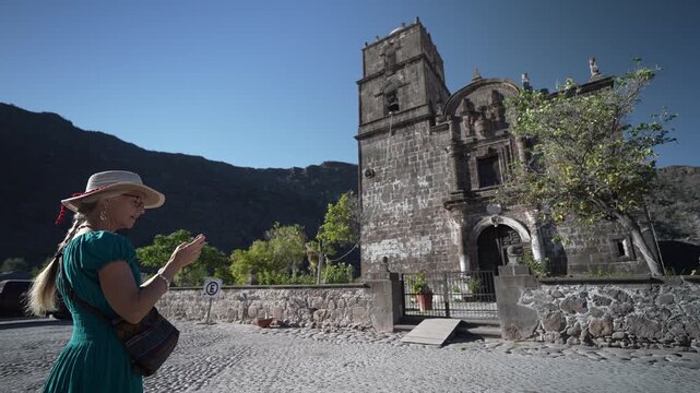 Senior woman happily takes photos with her phone at San Javier historic Mission in Baja California Sur, Mexico at sunrise