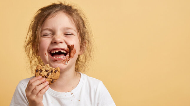 Laughing Young Girl Eating Chocolate Chip Cookie with Messy Face