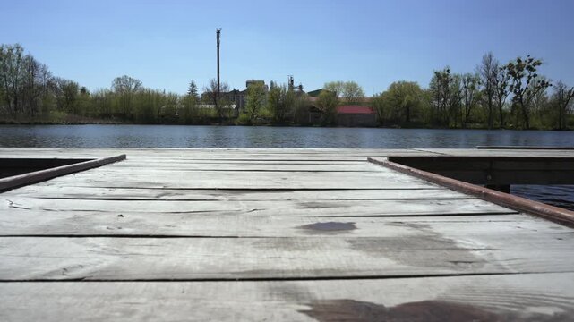 Two young women holding hands jumping from wooden pier into lake