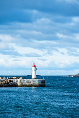 Obraz premium Lighthouse of norwegian town Vardo with blue sea and clouds in the background