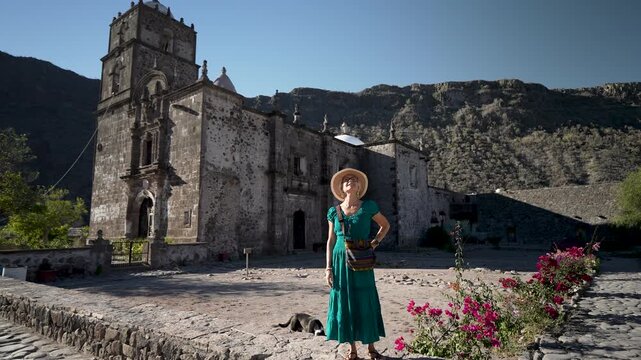 Senior woman walks through garden with excitement near historic San Javier Mission as the sun rises in Baja California Sur, Mexico