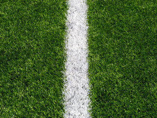 Fototapeta premium White painted line on green soccer turf closeup