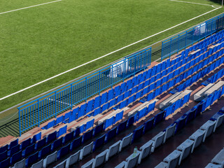 Blue and white stadium seats beside soccer field © Andrey
