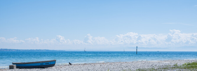 Fototapeta premium Blue rowboat resting on hörnle beach, lake constance