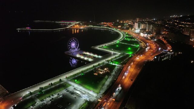 Aerial drone night view of Baku Boulevard, illuminated Ferris wheel and coastline, Azerbaijan