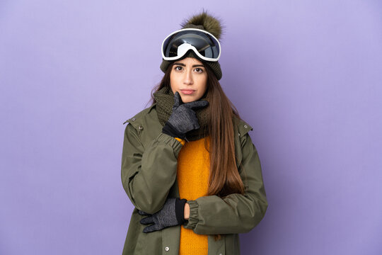 Skier caucasian girl with snowboarding glasses isolated on purple background thinking