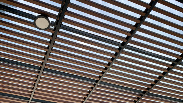 Modern wooden louver ceiling with metal frame and downlight. Contemporary exterior ceiling design with timber battens and integrated lighting.