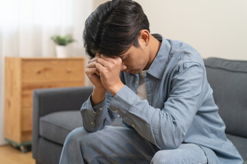 Fototapeta premium Stressed male feeling depressed and lonely on the sofa in the house.