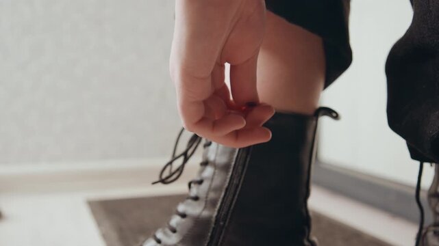 Closeup final adjustment of boot zipper and laces, hand tugs zipper, ankle cuff rolls, chunky sole on wooden floor, focused styling moment, urban confident ritual before stepping out, polished edgy