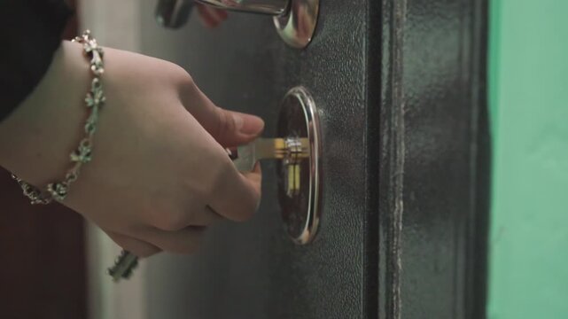 Hand turns key and opens door, lock releases with subtle click and handle movement, interior corridor revealed with warm light and relieved arrival, gentle step across threshold signaling return.