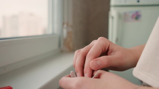 Detailed shot of hands sealing cigarette with lighter nearby outside window. Close perspective of hands carefully sealing and tamping cigarette beside city window with lighter on sill