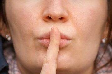 Fototapeta premium Woman making silence gesture with finger on lips