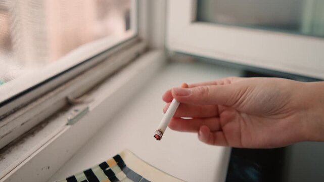 Closeup hand holding cigarette near window, night shift nurse taking brief pause, ashtray on sill, neon city glow and tired fingers, ember flicker, cinematic quiet and tiny relief