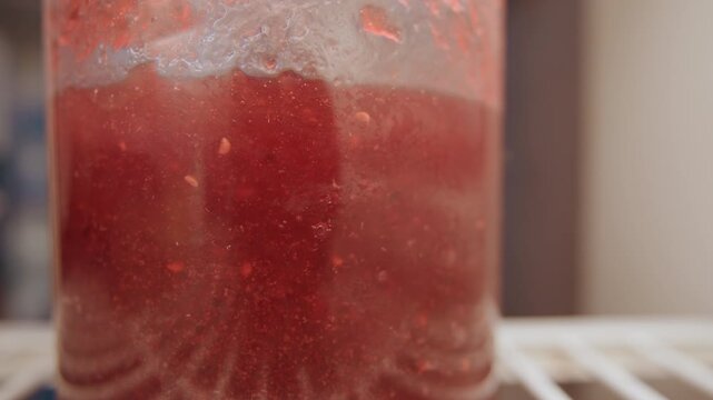 Preserving jar scene. Kitchen scene capturing jam preservation activity. An orderly kitchen during jam jar placement on shelf. Serene moment of preserving jam with blurred figure in background