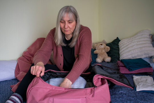 Senior woman organizing clothes inside suitcase while packing