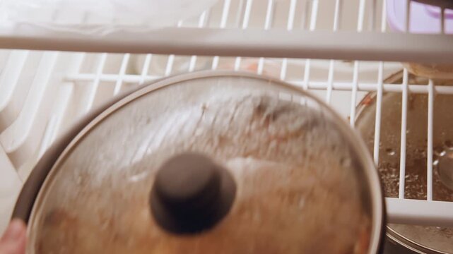 Cooked food stored. Kitchen shelf neatly organized items. Seasoned dish kept in clear container after preparation. Carefully arranged kitchen items including jars and pans in clean cabinet