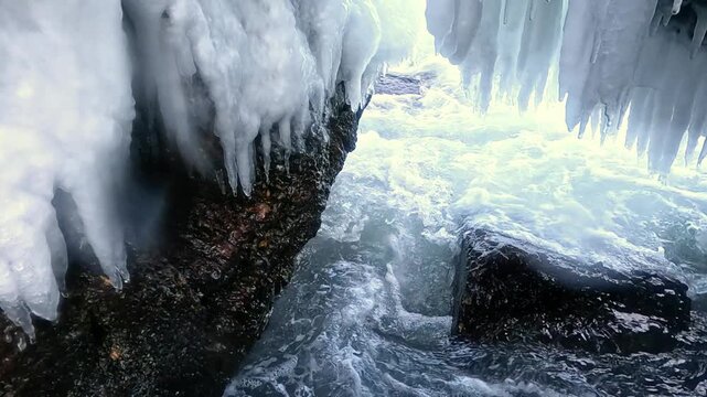 Ice stalactites formed inside a grotto within large coastal rocks after seawater spray freezing during winter conditions in the Black Sea