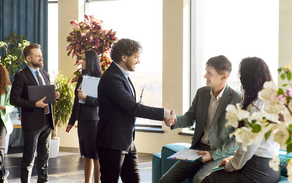 Business team handshake in office meeting. Colleagues welcome a partner and discuss plans in a bright workspace. Useful for partnership and teamwork. Clear message of agreement and teamwork.