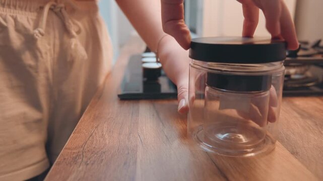 Clean jar on wooden counter. Elegant kitchen environment with neatly arranged jars and stove background. Idyllic culinary space showcasing tidy storage and warm ambient lighting in kitchen
