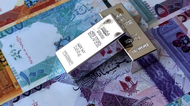 A silver bar, white metal against a backdrop of Qatari money, as a concept for the sales market. A silver bar as a background for your design