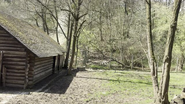 Old wooden log cabin surrounded by trees in a forest park during spring