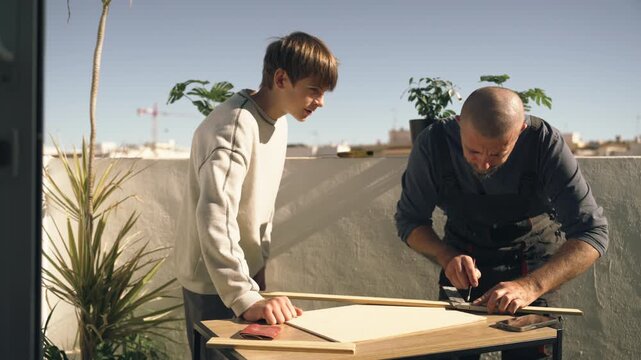 Caring father teaching teenage son how to measure and cut wood safely for a practical DIY project, emphasizing mentorship, patience, and life skills development.