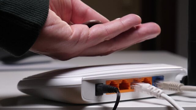 Hand holding several coins over a connected wi fi router, symbolizing the financial burden and expenditure associated with broadband internet, network services, and digital access fees